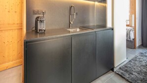 A modern kitchen with a stainless steel sink, a built-in coffee machine, and wooden cabinets. - Apartment in Saint-Sorlin with Mountain Views (Saint-Sorlin-d´Arves)