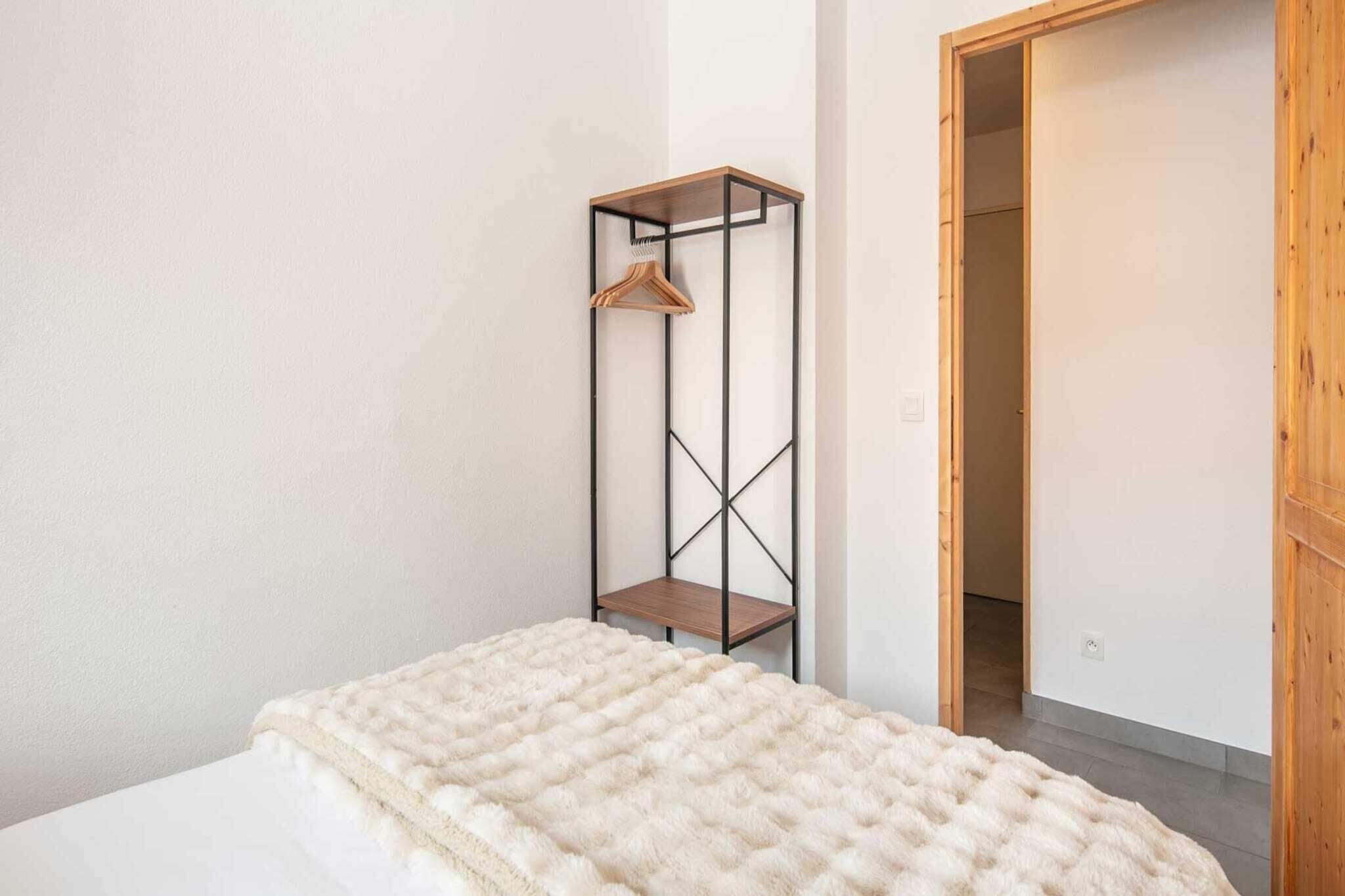 Een slaapkamer met een bed, een houten garderobe en een zwevende plank.