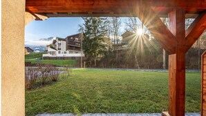 A wooden deck with a view of a modern building and a grassy area.