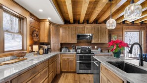 A kitchen with wooden cabinets, a stainless steel oven, and a large window. - 5BR Lodge w/ Hot Tub, Game Room, Great Views & Pet-Friendly (Banner Elk)