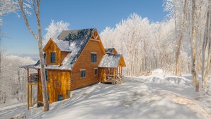 A wooden cabin with a sloped roof, surrounded by snow-covered trees. - 5BR Lodge w/ Hot Tub, Game Room, Great Views & Pet-Friendly (Banner Elk)