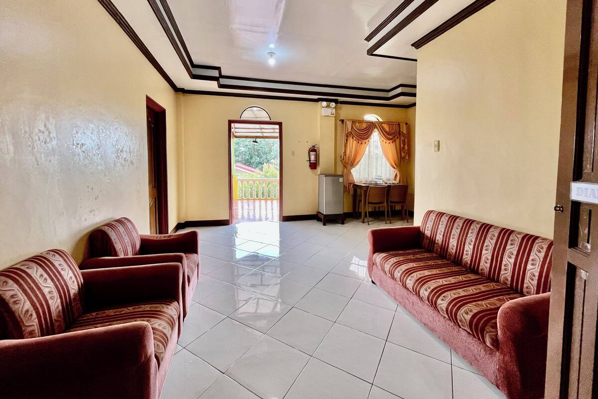 A hotel lobby with two sofas, a dining area, and a view of the outside.
