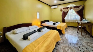 A hotel room with two beds, a desk, a chair, a window with curtains, and a patterned floor. - South Villa Apartelle Panglao Bohol (Panglao)