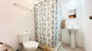 A bathroom with a toilet, shower curtain, sink, and a towel rack.