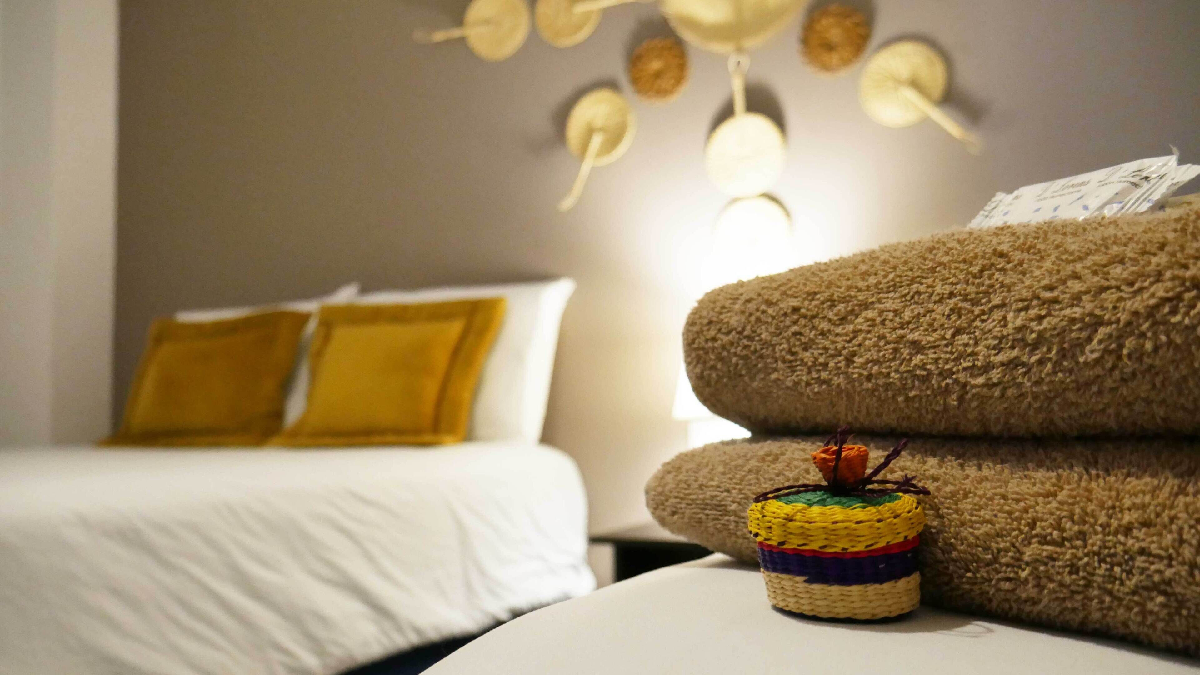 A hotel room with a bed, a sofa, and a wall-mounted light fixture.
