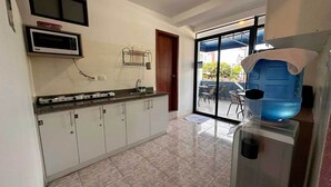 A kitchen with a microwave, a water dispenser, and a sink. - Park View Hostel & Suites (Manta)