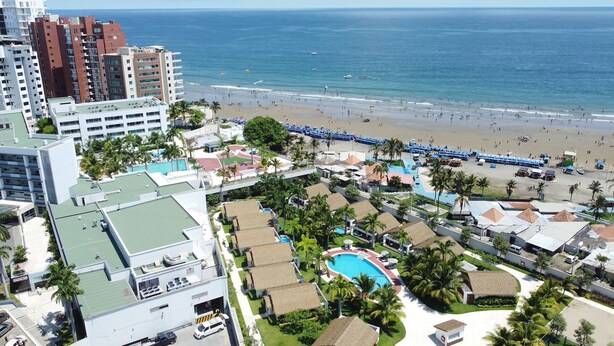 A resort with a beach, a swimming pool, and high-rise buildings in the background. - Park View Hostel & Suites (Manta)
