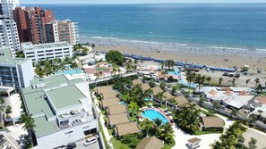 A resort with a beach, a swimming pool, and high-rise buildings in the background.
