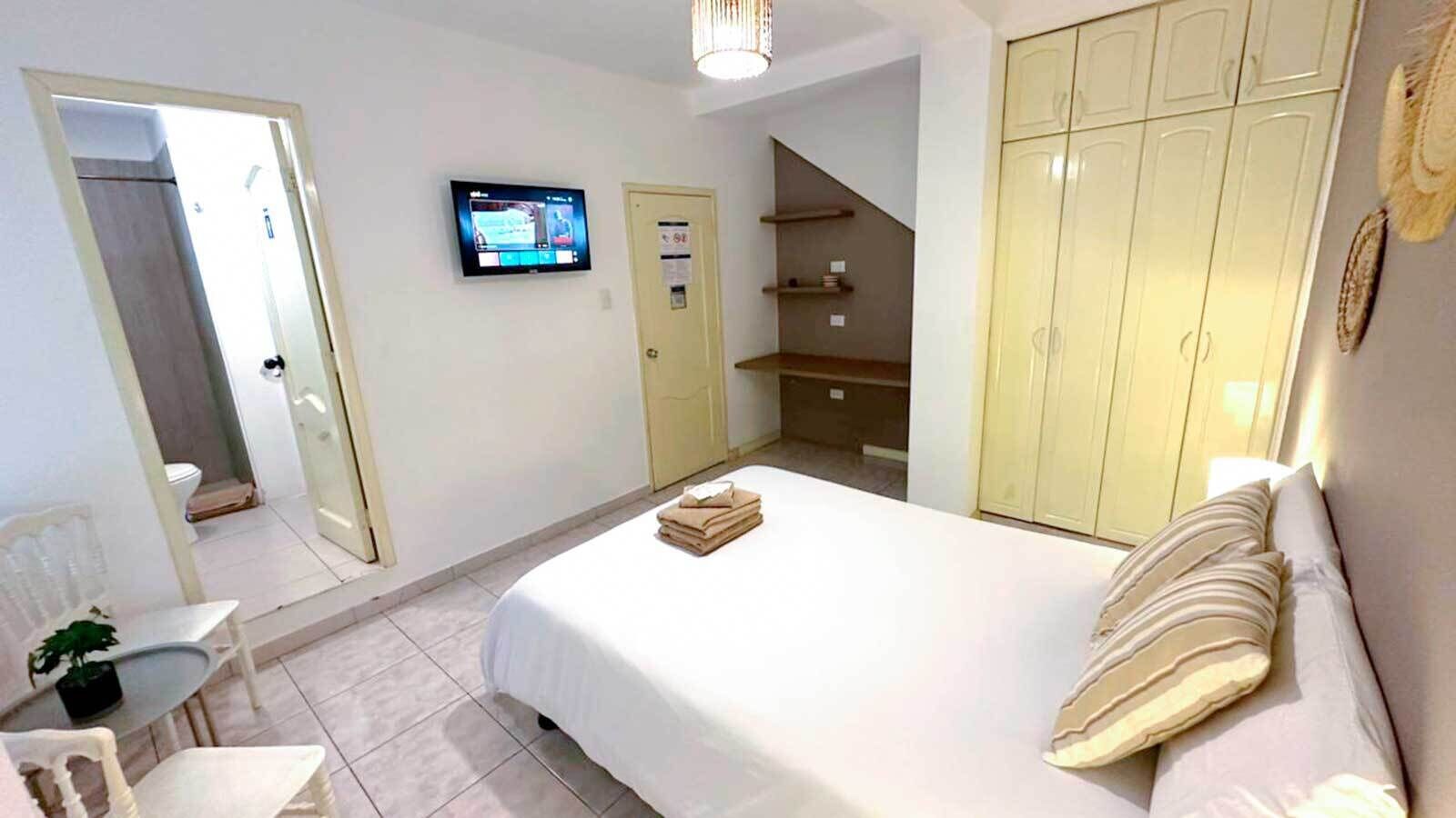 Een hotelkamer met een bed, een televisie, een kledingkast, een bureau en een stoel.