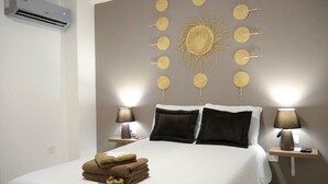 A bedroom with a bed, two bedside tables, a wall-mounted decorative item, and a wall-mounted air conditioner. - Park View Hostel & Suites (Manta)