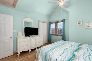 A bedroom with a bed, a dresser, a television, a ceiling fan, and a window with curtains. - A Bbitt Beachy: Oceanside, Hot Tub, Community Pool, Easy Beach Access (Nags Head)