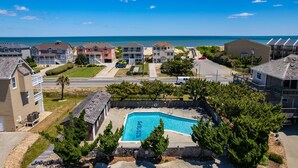 A residential area with a swimming pool surrounded by trees and houses. - A Bbitt Beachy: Oceanside, Hot Tub, Community Pool, Easy Beach Access (Nags Head)
