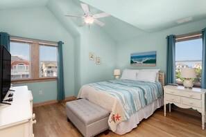 Une chambre à coucher comprenant un lit, une table de chevet, un bureau, une chaise et un ventilateur de plafond.