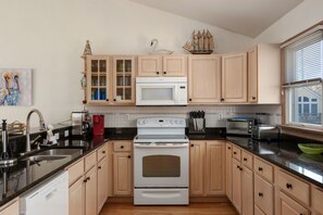 A kitchen with wooden cabinets, a white stove, a microwave, and a toaster.