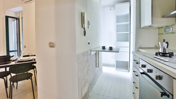 A modern kitchen with white cabinets, a built-in oven, and a countertop with a coffee maker.