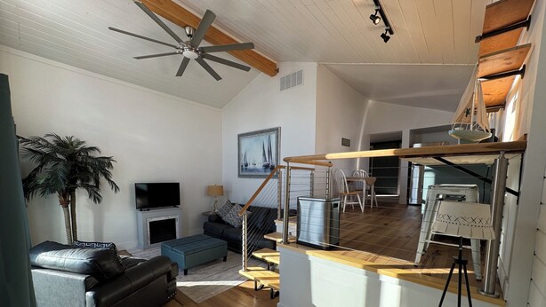 A modern living room with a black leather sofa, a television, a fireplace, and a large window. - Charming log cabin (Spring Lake)