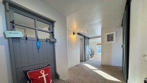 A hallway with a bench, a sign reading "be our guest," and a door leading to a laundry area. - Charming log cabin (Spring Lake)