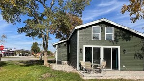 A two-story house with a patio and sliding glass doors. - Charming log cabin (Spring Lake)