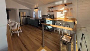 A modern kitchen with wooden flooring, stainless steel appliances, and a bar area. - Charming log cabin (Spring Lake)