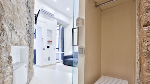 Un baño moderno con una pared de acento de piedra, un radiador blanco y un separador de vidrio.