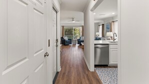 A hallway leading to a living area with a ceiling fan, a dining area with a table and chairs, and a kitchen with a sink and cabinets. - Dog Friendly, Steps away from the beach, Restaurants, Village, and Pier. (Saint Simons Island)