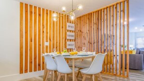 A dining area with a wooden slat partition, a table set for four, and a modern chandelier. - 8Guest, 5 minutes to everything in Miami (Miami)