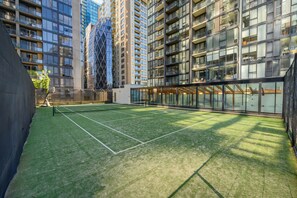 A tennis court surrounded by high-rise buildings with large windows. - The Sentinel Retreat (Southbank)