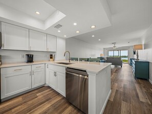 A modern kitchen with white cabinetry, a stainless steel dishwasher, and a breakfast bar.