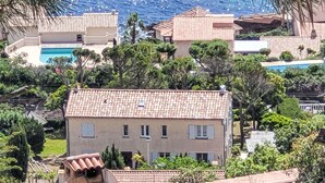 A Mediterranean-style building with a tiled roof, surrounded by lush greenery and a pool in the background. - Boudi..ou by Interhome (Anthéor)