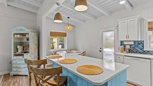 Une cuisine dotée d’un îlot central, de meubles blancs et d’un mur d’accent bleu.