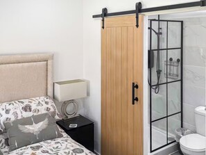 A bedroom with a bed, nightstand, and a wooden wardrobe with a sliding door.