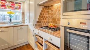 Une cuisine moderne avec des meubles blancs, un dosseret carrelé, une cuisinière et un four.