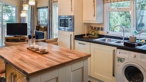 Una cucina moderna con isola in legno, forno a microonde integrato, lavastoviglie e lavatrice.