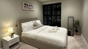 Um quarto moderno com uma cama, mesa de cabeceira, luminária e um espelho grande.