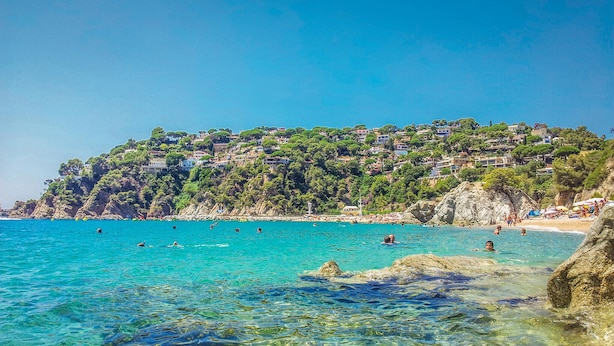 A coastal scene with clear turquoise water, rocky shore, and a hillside with buildings. - Awesome home in Vidreres (Vidreres)