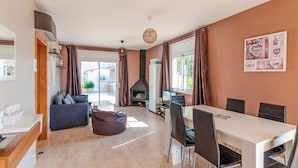 A modern living room with a sofa, a dining table with chairs, a fireplace, and a large window. - Awesome home in Vidreres (Vidreres)