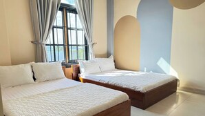 A bedroom with two wooden beds, a large window with curtains, and a view of greenery outside. - Doi Ngoai Bien Phong SPA Hotel (Buon Ma Thuot)
