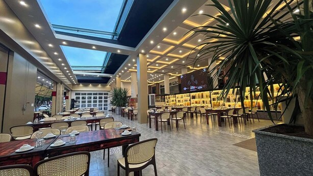 A spacious indoor dining area with high ceilings, a skylight, and a variety of seating arrangements. - Doi Ngoai Bien Phong SPA Hotel (Buon Ma Thuot)