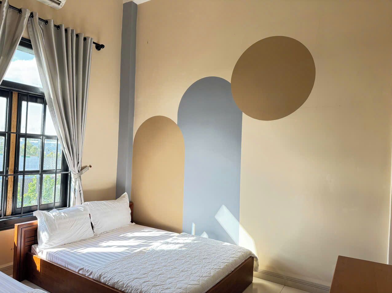 Een slaapkamer met een bed, gordijnen en een raam.