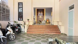 A hotel lobby with a reception desk, a staircase leading to the upper floor, and several parked scooters. - Doi Ngoai Bien Phong SPA Hotel (Buon Ma Thuot)