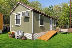 A small, single-story building with a ramp leading to the entrance, a small porch area, and a wooden deck.