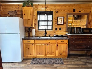 Una cocina tipo cabaña de madera con refrigerador, pileta, estufa y microondas.