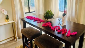 A dining table with pink flower petals, a potted plant, and wine glasses. - 2-bedroom villa with WiFi, AC in St. Lucia-Beach, Falls,Pitons, Mud Bath (Laborie)