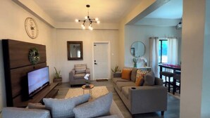 A living room with a TV, sofas, a coffee table, and a chandelier. - 2-bedroom villa with WiFi, AC in St. Lucia-Beach, Falls,Pitons, Mud Bath (Laborie)