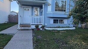 Una casa de dues plantes amb un porxo davanter i un petit jardí.