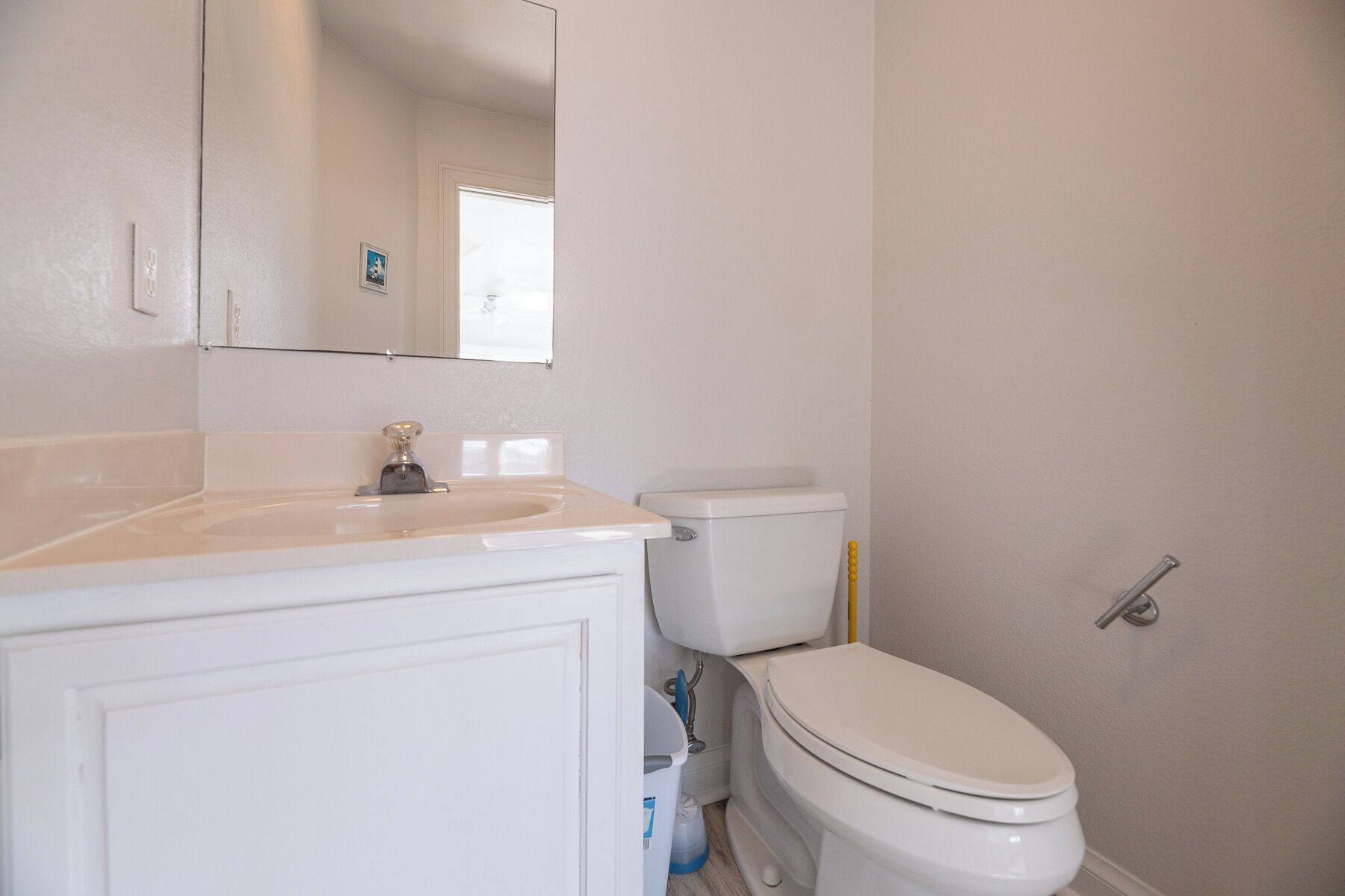 A bathroom with a white sink, toilet, and mirror.