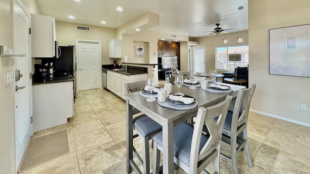 Une cuisine spacieuse avec un coin repas, comprenant un grand îlot central, des meubles blancs et un luminaire moderne au plafond.