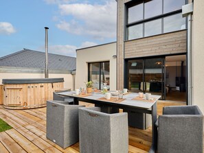 A modern outdoor patio with a wooden deck, a hot tub, and a table set for dining. - L'Aventure Gouvillaise by Interhome (Gouville-sur-Mer)