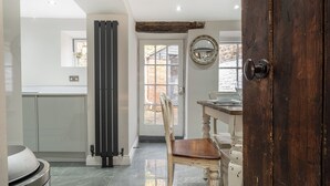 Een keuken met een groot raam, een houten deur en een eettafel met stoelen.