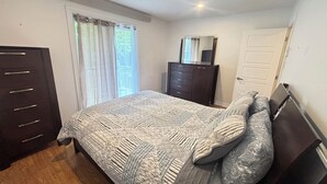 A bedroom with a bed, a dresser, a mirror, and a door.